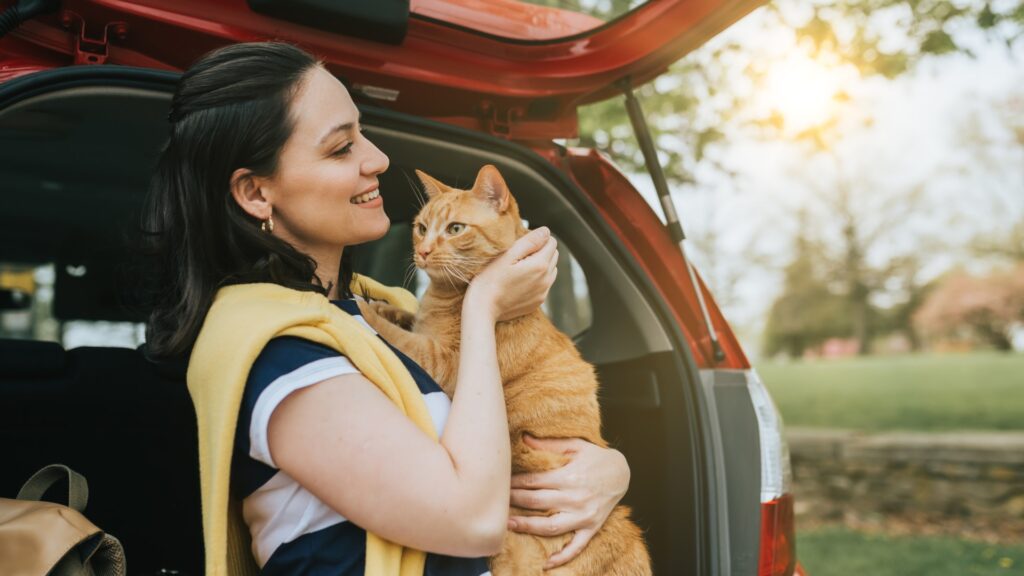 uśmiechająca się kobieta trzymająca kota na rękach na dworze